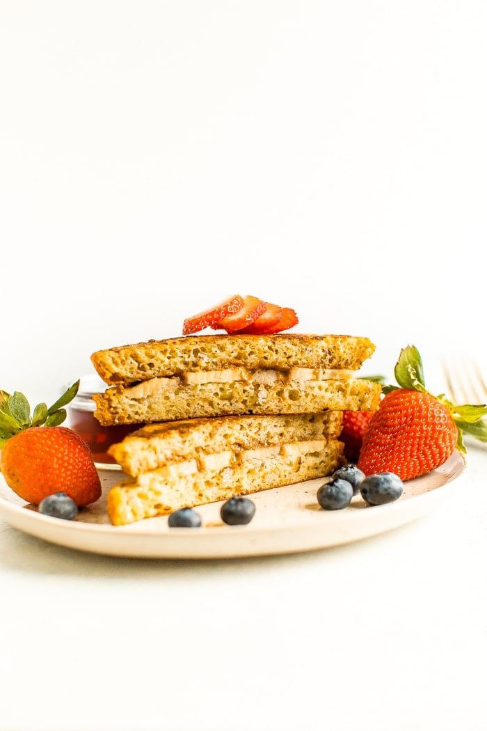 Stuffed French toast on a plate with strawberries and blueberries.