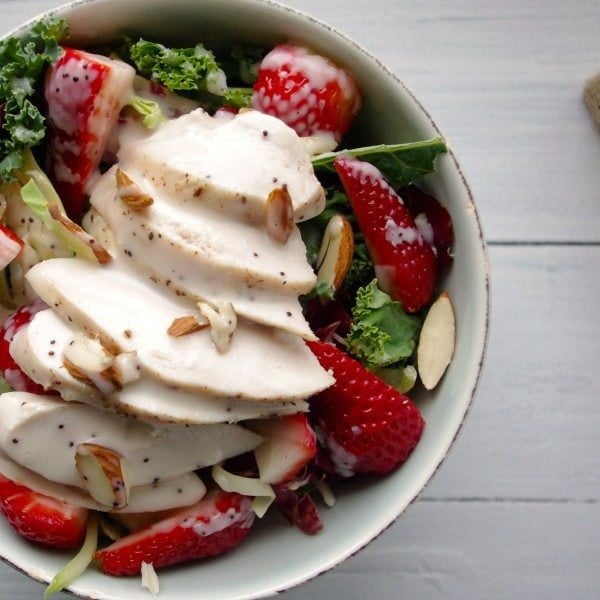 Strawberry Kale Slaw Chicken Salad with Poppyseed Dressing in white bowl on white wood table