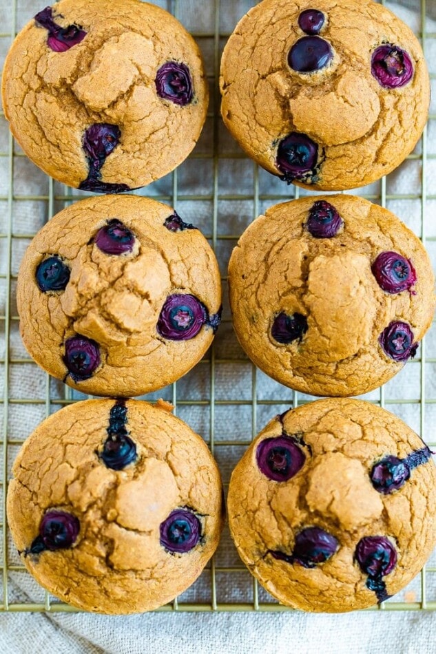 Six blueberry muffins on a cooling rack.