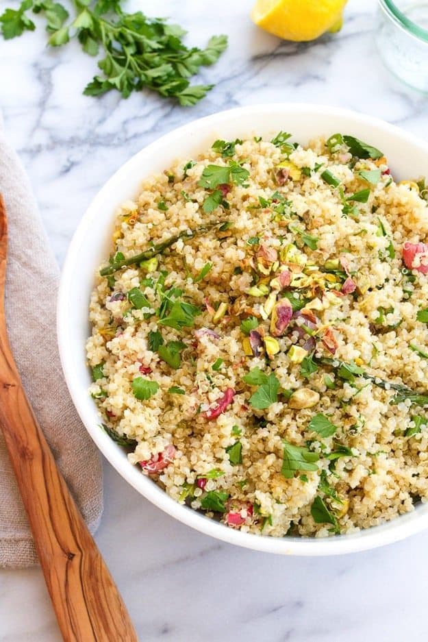 A bowl of spring quinoa salad. A wooden spoon is next to the bowl.