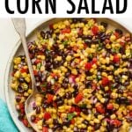 Serving bowl with black bean and corn salad. Spoon is in the bowl.