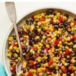 Serving bowl with black bean and corn salad. Spoon is in the bowl.