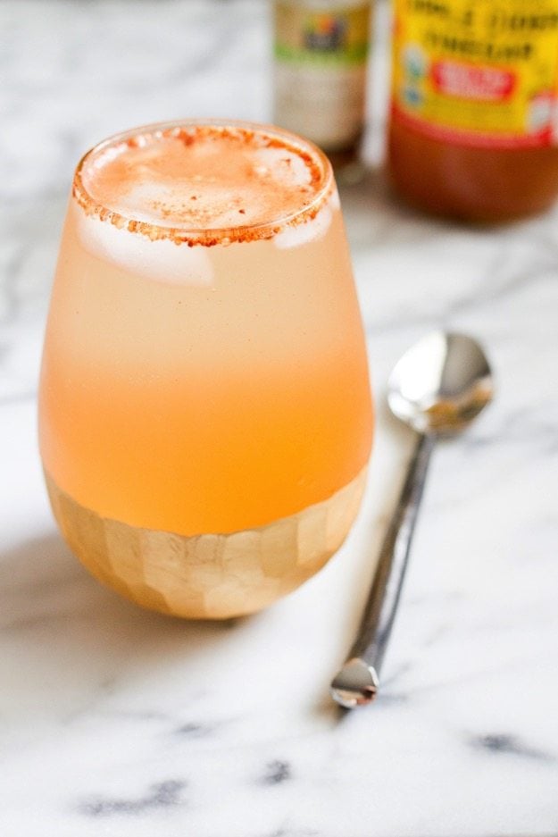 Apple Pie Apple Cider Vinegar Drink in a shallow glass sitting on a marble countertop with a silver spoon next to it. 