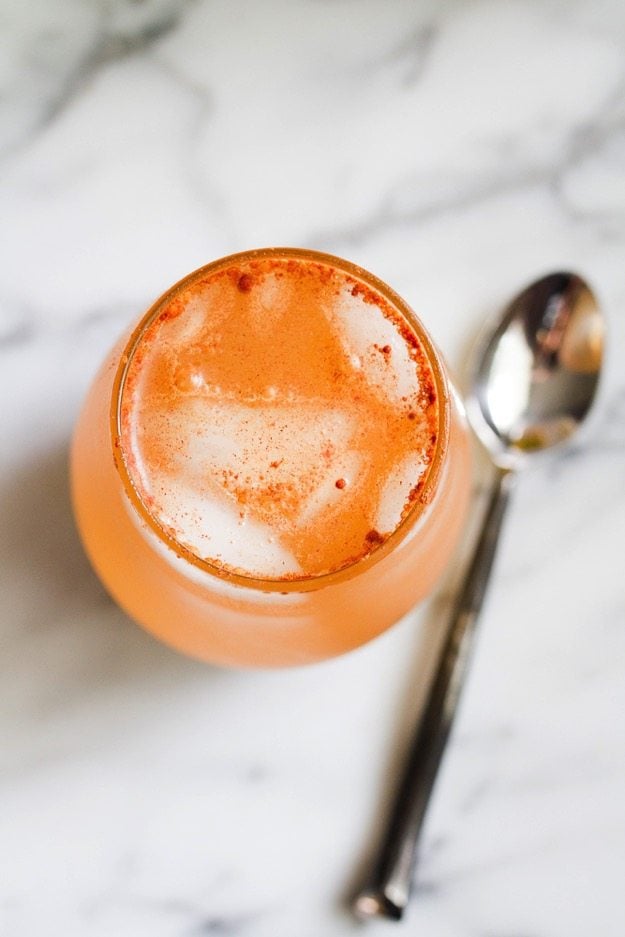 Overhead shot of an Apple Pie Apple Cider Vinegar Drink on a marble countertop with a silver spoon sitting next to it. 