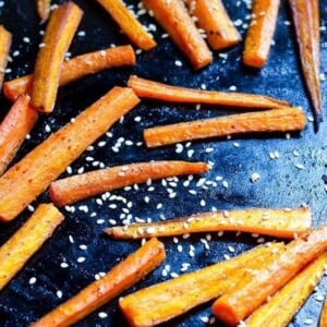Sheet pan with slices of carrot sprinkled with sesame seeds.