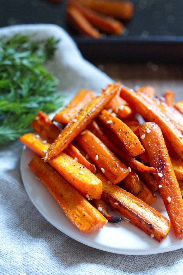 White plate with sesame roasted carrots piled atop it.