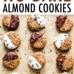 Cookie sheet lined with parchment paper. 9 no bake almond cookies half dipped in dark chocolate or white chocolate and sprinkled with cacao nibs.