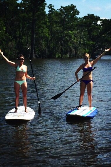 Two women paddle boarding on the water.
