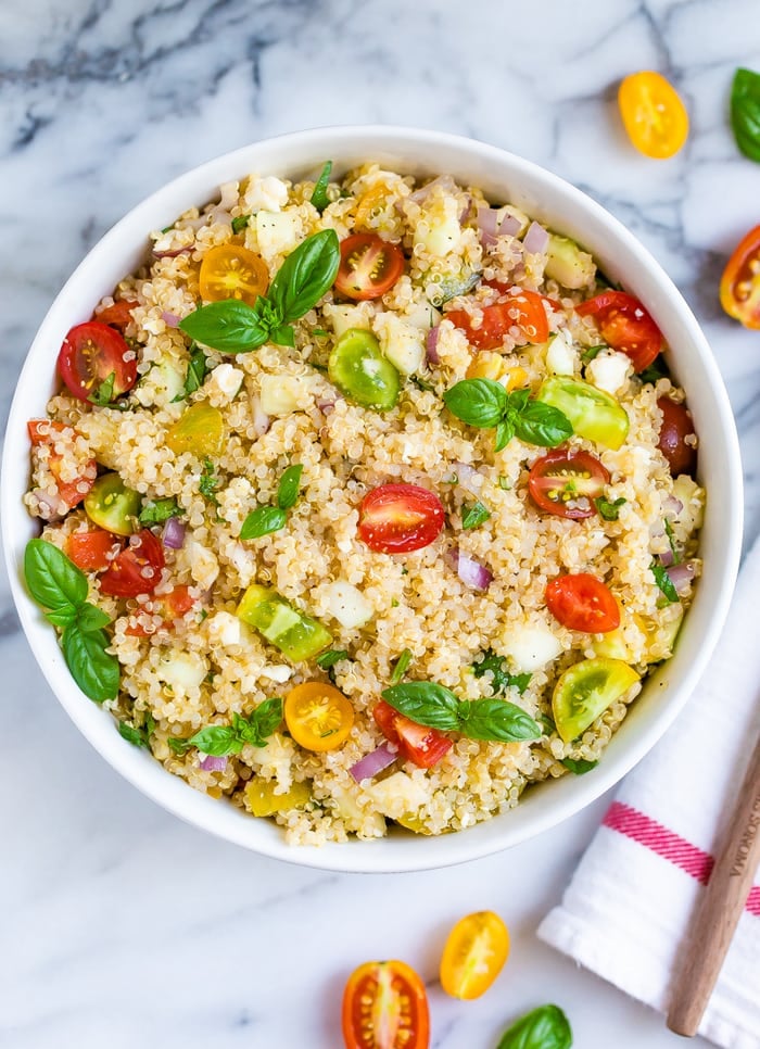 Bowl with Greek quinoa salad made with tomatoes, basil, red onion, feta, and quinoa.