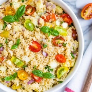 Bowl with Greek quinoa salad made with tomatoes, basil, red onion, feta, and quinoa.