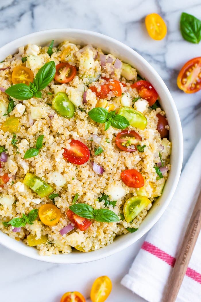 Bowl with Greek quinoa salad made with tomatoes, basil, red onion, feta, and quinoa.