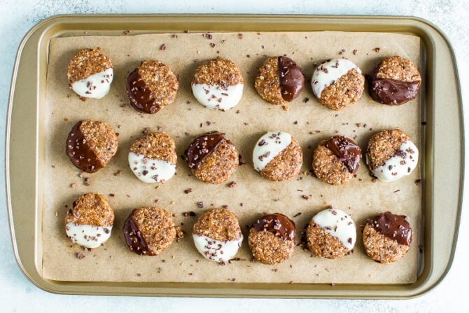 No bake almond cookies half dipped in white and dark chocolate on a cookie sheet lined with parchment paper.