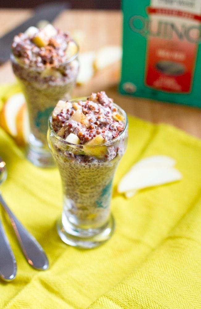 A glass jar of overnight quinoa is in focus with a blurry glass in the background.