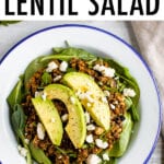 Plate with a bed of fresh spinach topped with a warm Mediterranean salad, topped with feta and avocado.