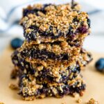 Stack of four blueberry crumble bars with an oat and hemp seed crumble topping.