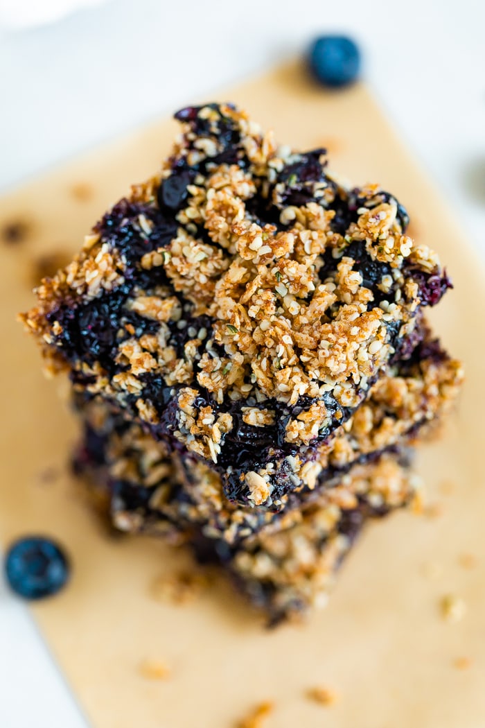 Stack of blueberry crumble bars. Close up of the top of the bar with an oat and hemp seed crumble.