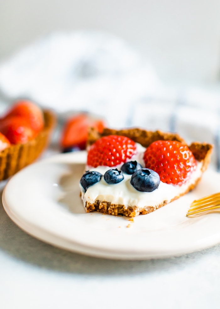 Slice of greek yogurt bery party on a plate with a fork bite taken out of it.