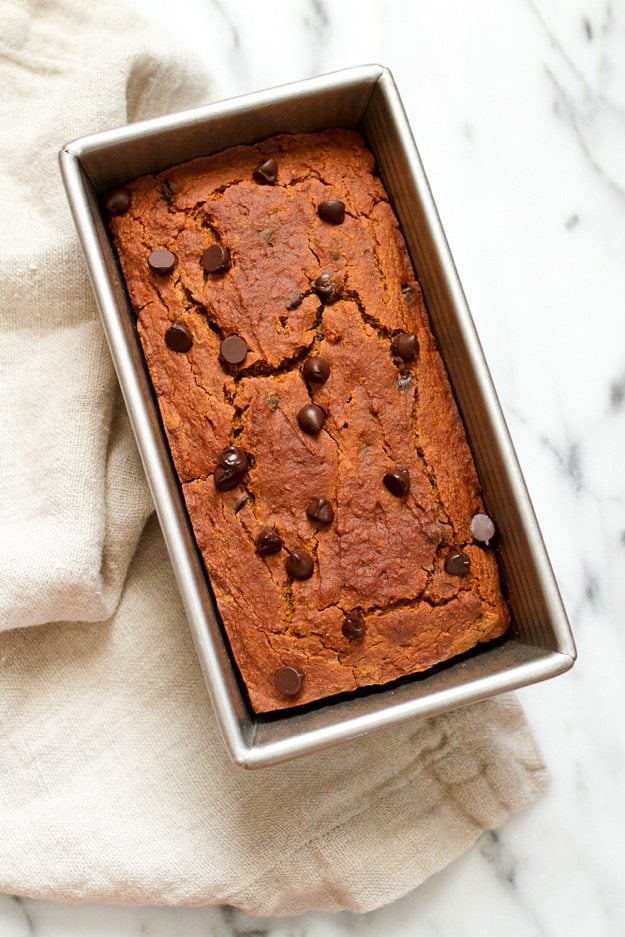 Quinoa flour pumpkin bread in a bread pan resting on a linen towel.