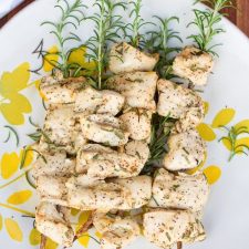 A plate of grilled rosemary chicken skewers.