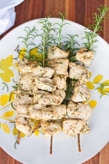 A plate of grilled rosemary chicken skewers.