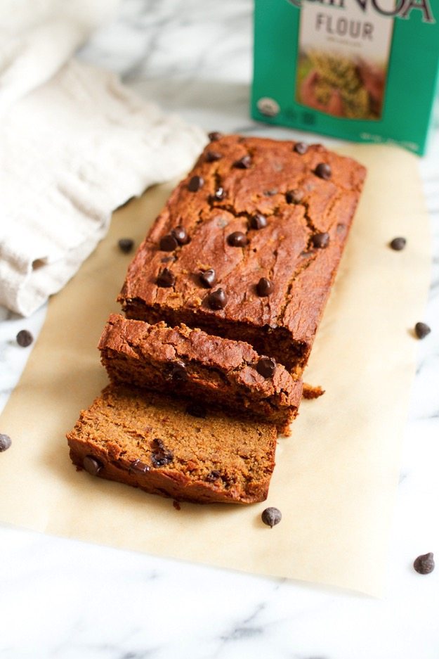 Sliced loaf of quinoa flour pumpkin bread on a piece of parchment paper.