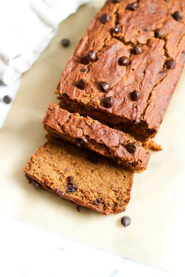 Sliced loaf of quinoa flour pumpkin bread on a piece of parchment paper.