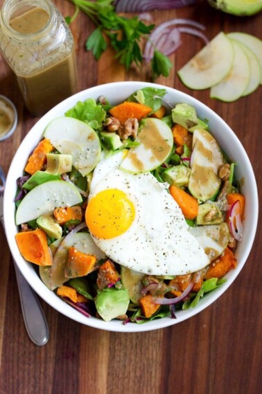 Fall breakfast salad in a bowl with apples, avocado, squash, onion, and walnuts on greens.