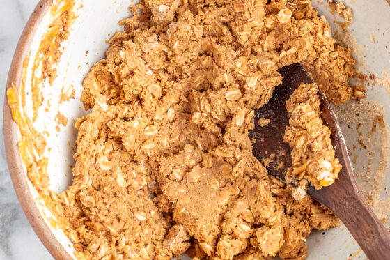 Ingredients for pumpkin protein bars mixed together with a wooden spoon.