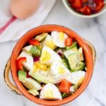 Chopped hard boiled egg and avocado with chopped peppers and onions in a bowl.