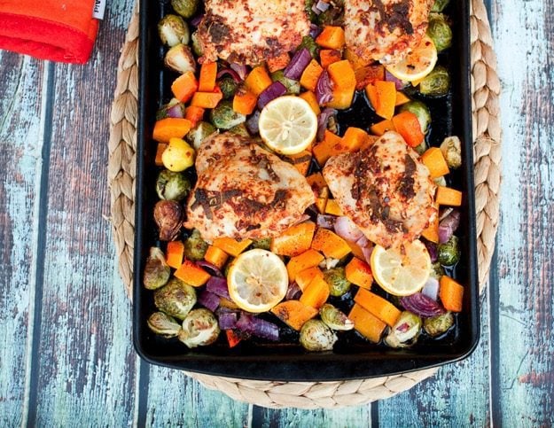 Sheet pan with baked chicken, butternut squash cubes, red onion and Brussels sprouts.