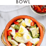 One bowl with chopped hardboiled eggs, avocado, and vegetables, another bowl with chopped peppers and onions, hardboiled egg on the side.