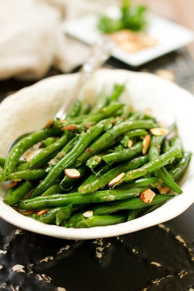 Green beans with shallots and almonds in a white serving bowl.