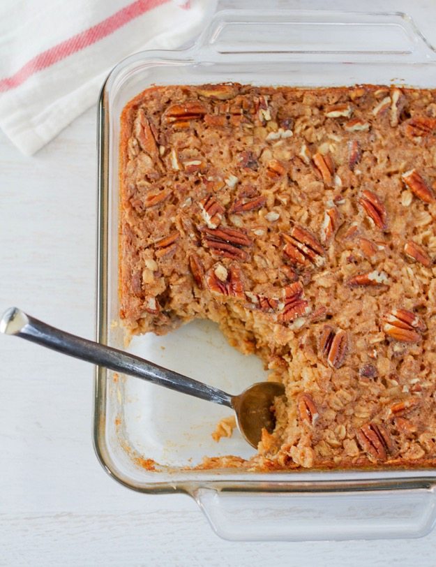 Baking dish with maple pecan baked oatmeal. A spoon has scooped out a serving.