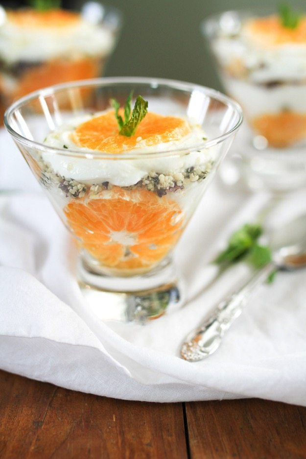 A side view of a glass bowl with clementine slices and greek yogurt parfait.