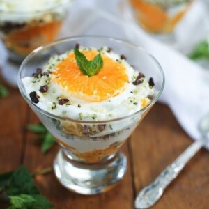 Glass bowl of clementine greek yogurt parfait with two other bowls in the background.