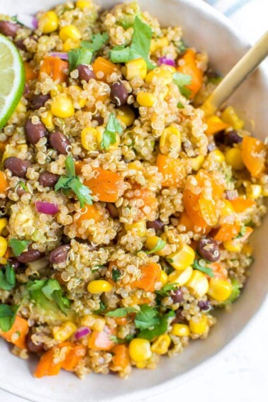 Bowl of quinoa salad with corn, sweet potatoes, corn, cilantro, and black beans.