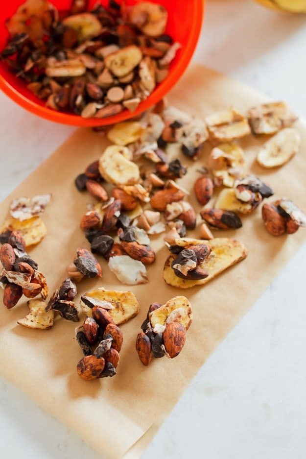 Trail mix on parchment paper. Banana chips, chocolate chips, coconut flakes and almonds.