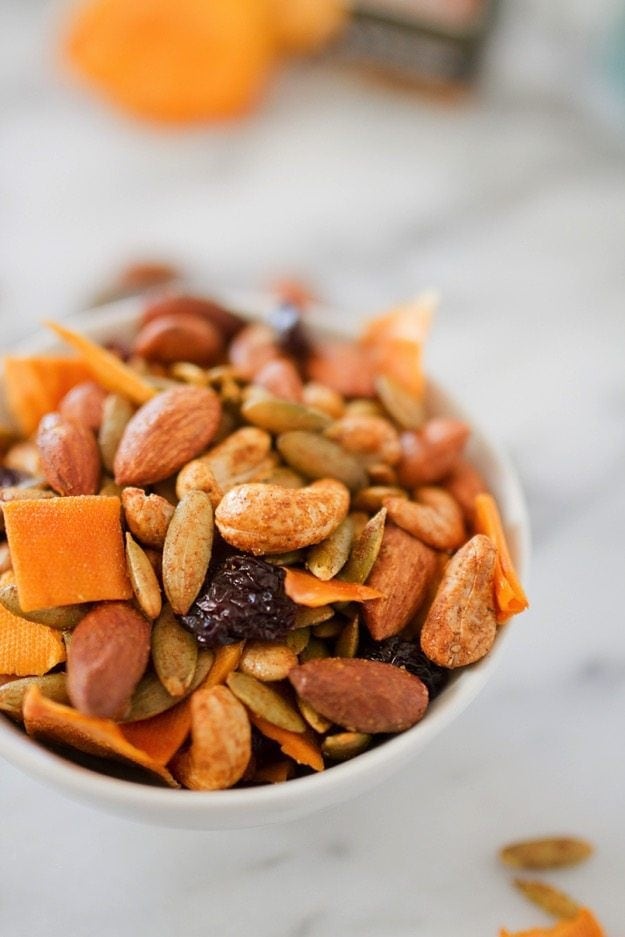 Mango curry trail mix in a white bowl on a marble counter. 