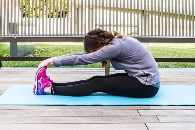 Girl on yoga mat doing a forward fold stretch. 
