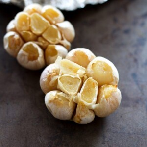 Two heads of garlic on a baking sheet.