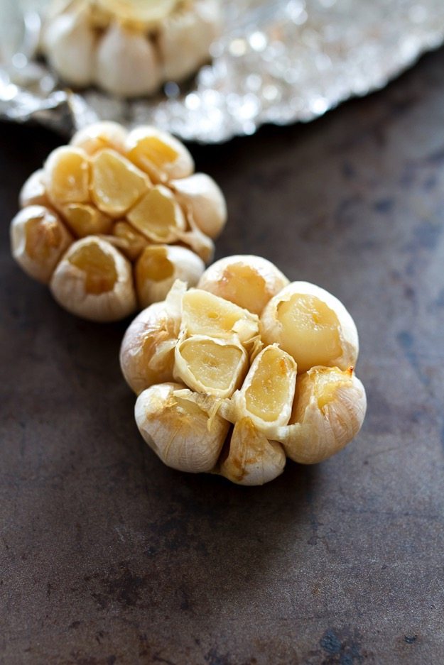 Two heads of garlic on a baking sheet.