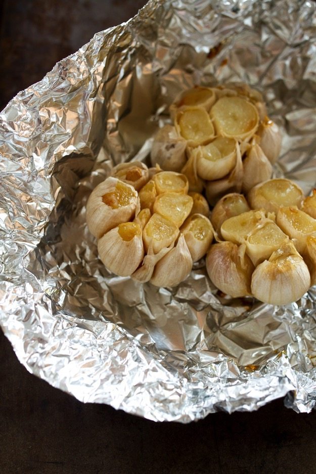 Three heads of garlic in aluminum foil after roasting. 