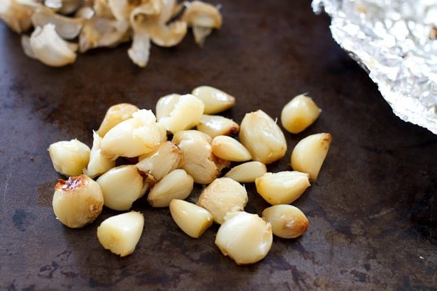 Roasted garlic that's been peeled on a baking pan.