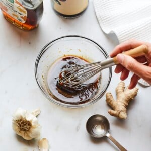 Whisking together teriyaki sauce in a small glass bowl.