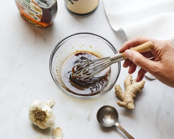 Whisking together teriyaki sauce in a small glass bowl.
