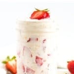 Glass jar of strawberry overnight oats topped with strawberry slices.