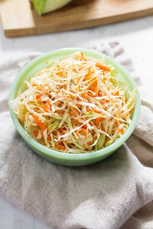 Cabbage and carrot slaw in a mint green bowl.