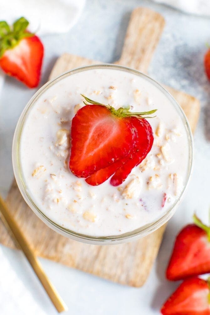 Top view of a jar of creamy strawberry overnight oats topped with strawberry slices.