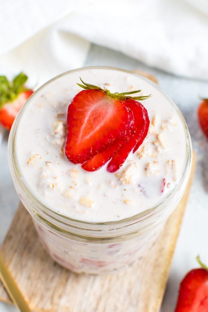 Top view of a jar of creamy strawberry overnight oats topped with strawberry slices.