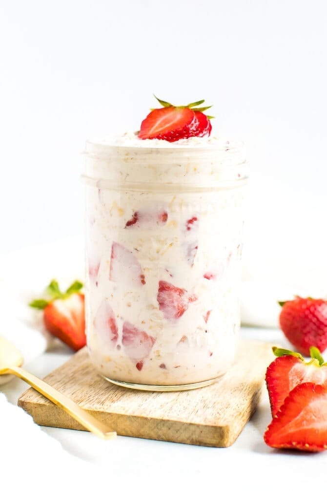 Jar of strawberry shortcake overnight oats with chunks of strawberries and topped with sliced strawberries.